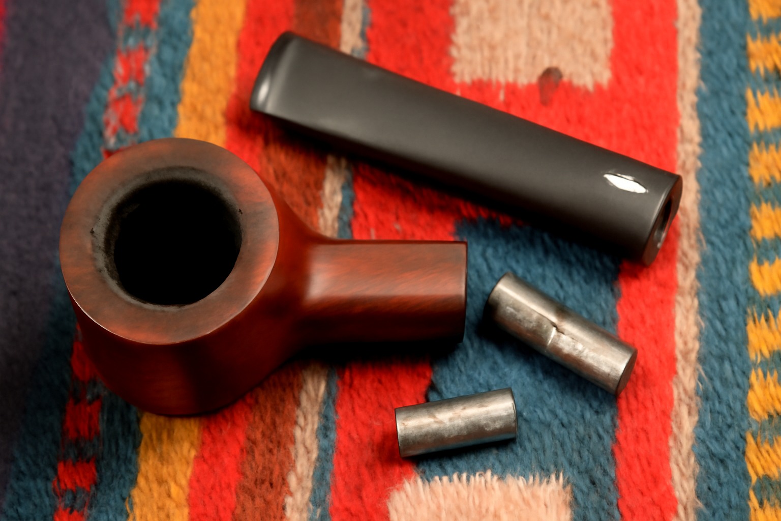 Disassembled wooden pipe with metal tenons on colorful fabric